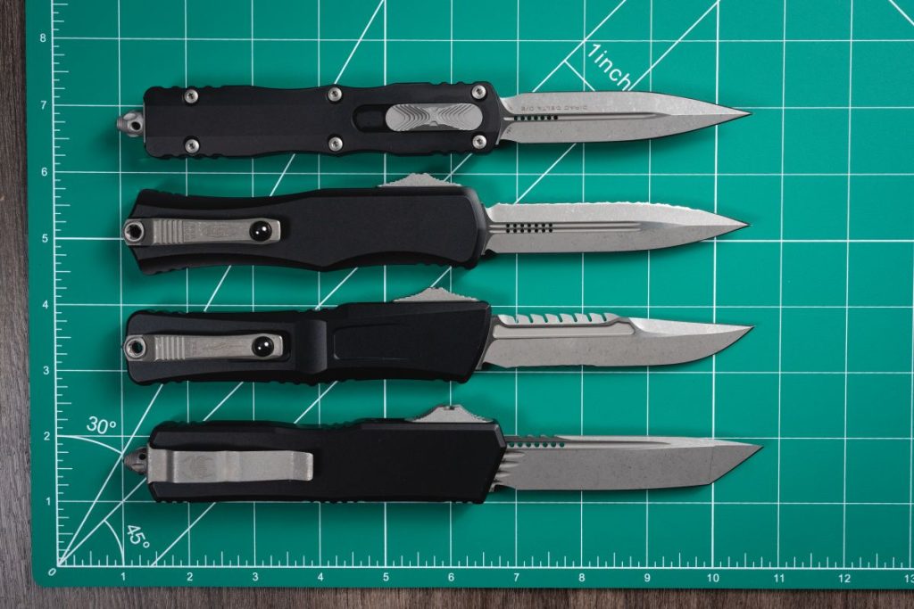 All large Microtech OTF knives lined up on a green mat