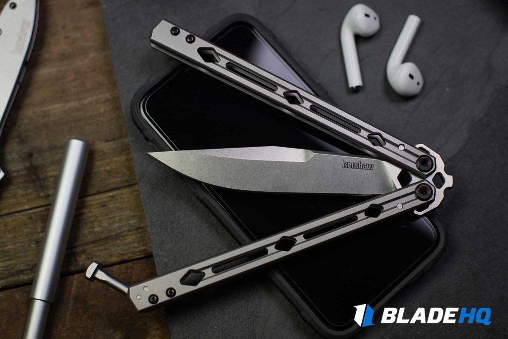 The Kershaw Lucha on someone's phone with their wireless headphones nearby.