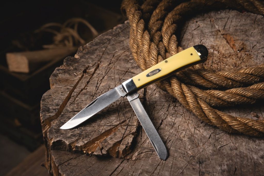 A large Case Trapper with yellow Delrin handle scales on a stump with rope.