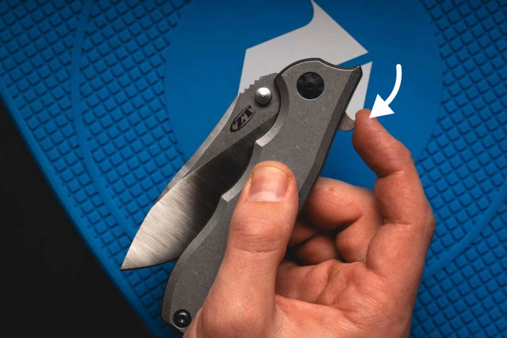A man pressing the flipper tab on a ZT Hinderer pocket knife.