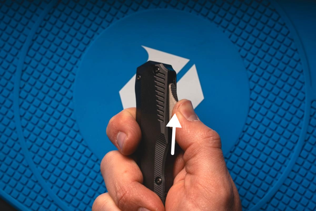 A man pushing up the slide on a Kershaw Livewire OTF knife.