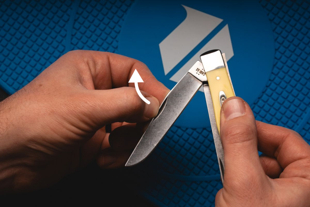 A man opening a Case Trapper knife with a yellow handle.