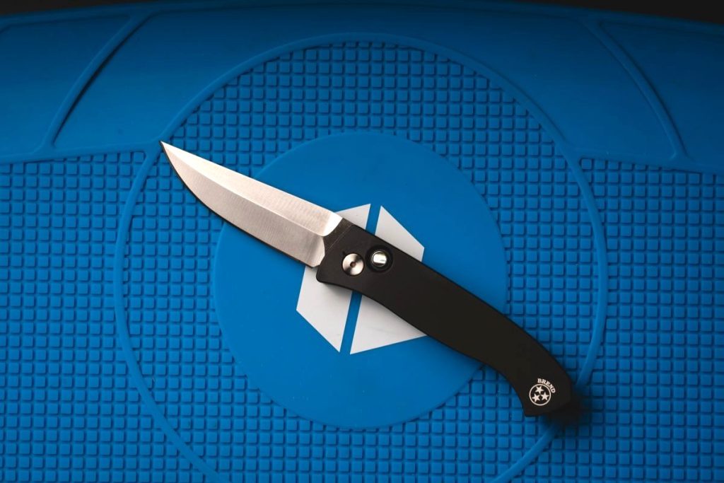 A Pro-Tech Brend automatic knife on a blue Blade HQ shop mat.