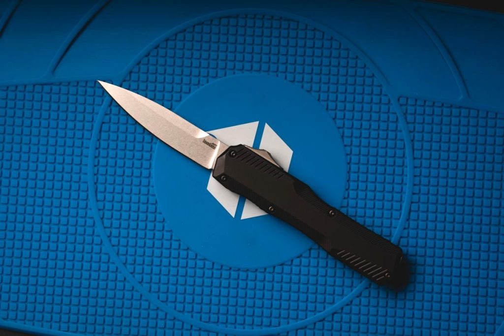 A Kershaw Livewire OTF knife on a blue Blade HQ shop mat.