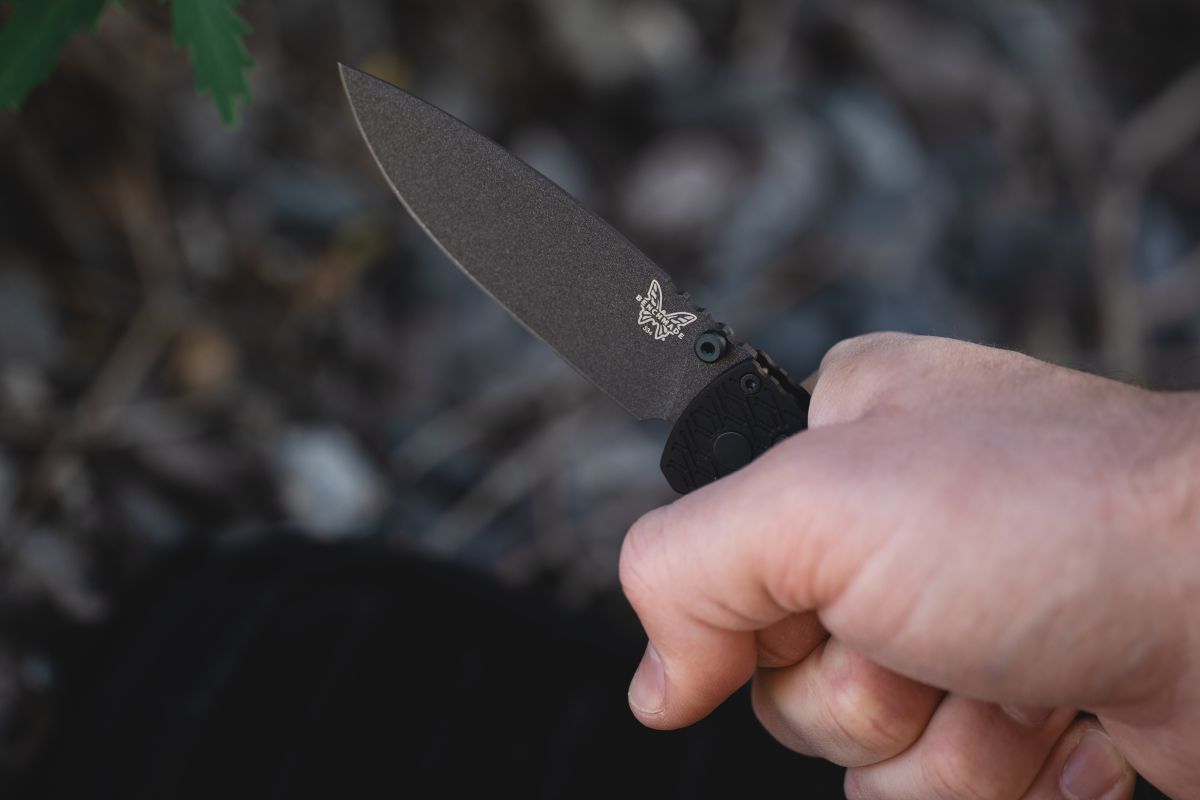 The Benchmade Bugout Vapyr in a man's grip against a blurred natural background.