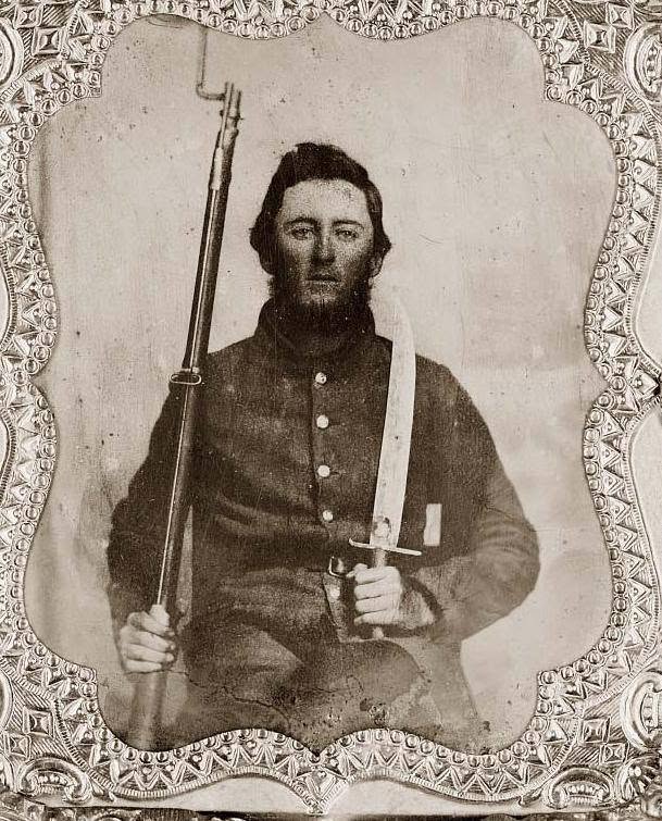 Historical photo of a Rezin P. Bowie holding a rifle and a large Bowie-style knife.