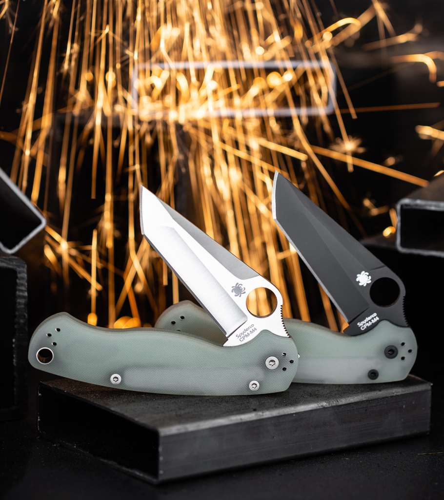 Two Blade HQ exclusive PM2 Tanto knives with M4 blades and jade G-10 handle scales. One has a black blade, and the other is satin. There are sparks in the background.