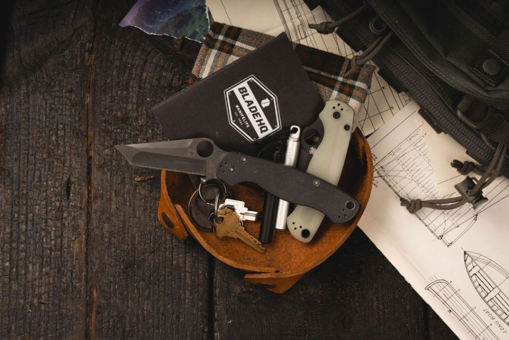 Two PM2 tanto knives in a leather container with keys, notebook, and other gear.