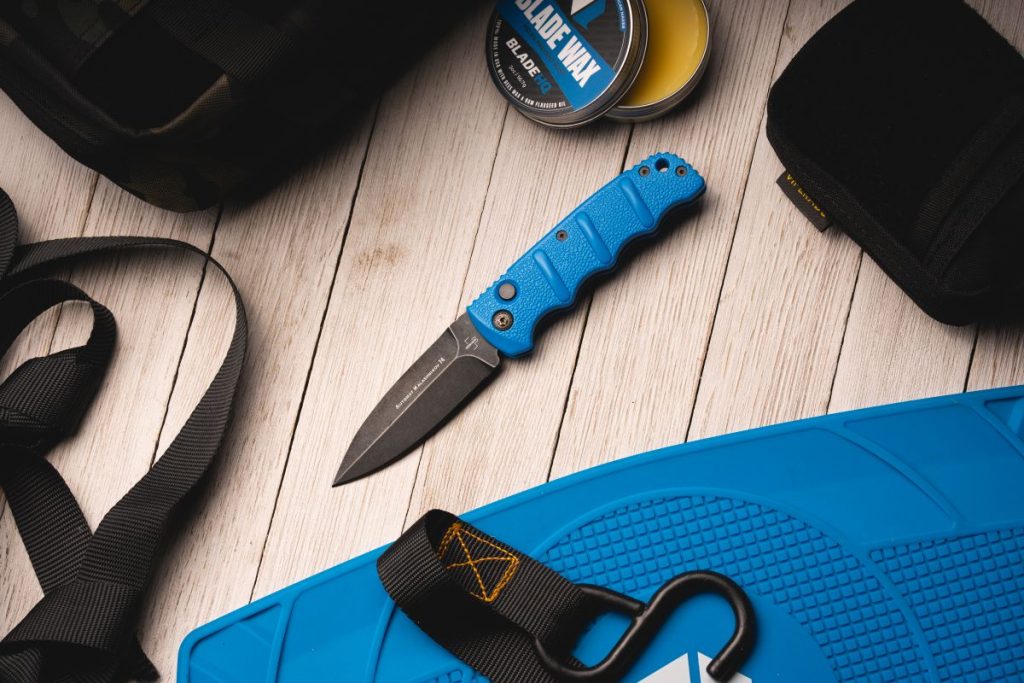 A blue Boker Kalashnikov with a black blade on a table.