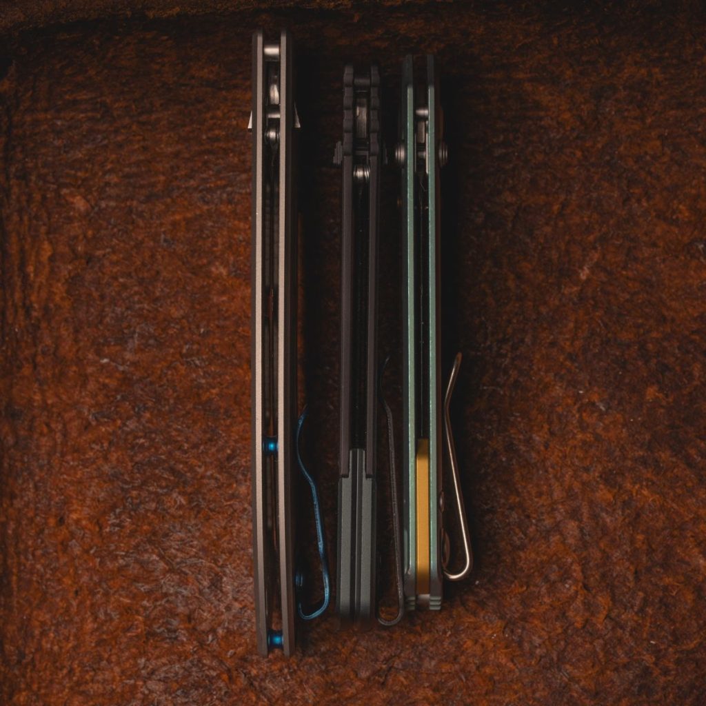 The Benchmade Narrows, Benchmade Bugout Vapyr, and Vosteed Parallel side by side, showcasing their comparably thin handles. Leather background.