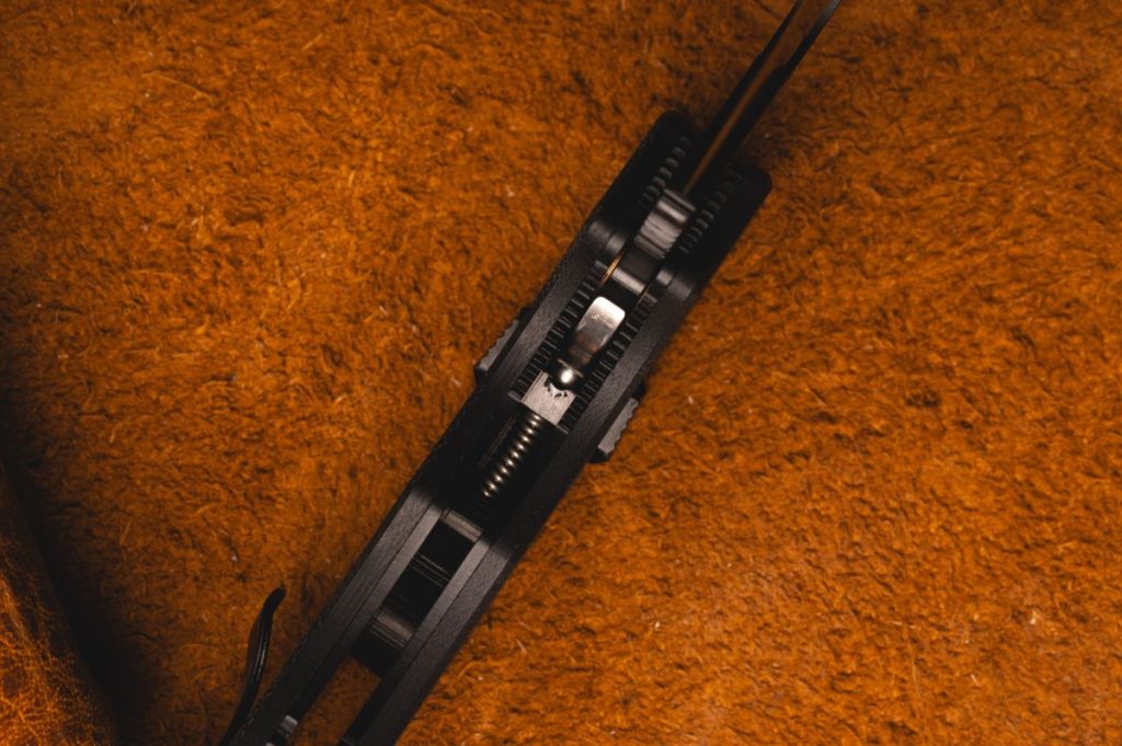 An up-close shot of the inside of a partially closed Sypderco Manix 2. The focus is on the small ball bearing inside the locking mechanism. 