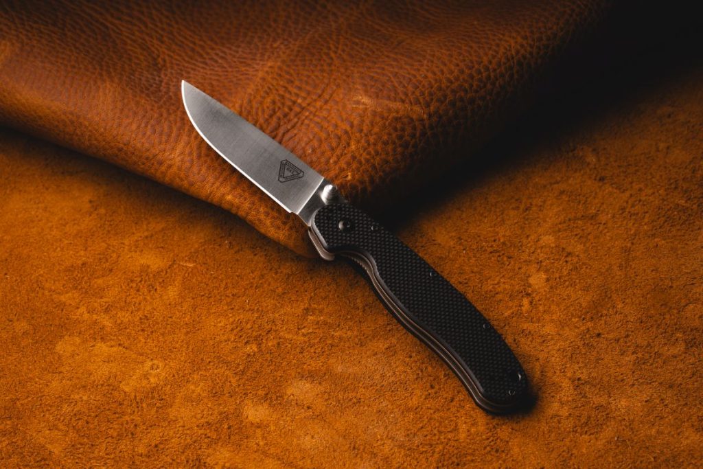 An Ontario RAT 1.5 rests on a leather background, its liner lock displayed.