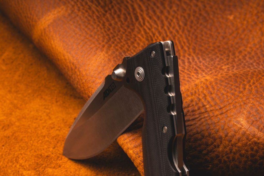 A Cold Steel Demko AD-10 on a leather mat. The Tri-Ad lock is prominent.