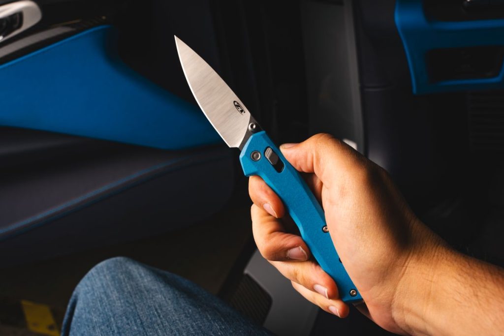 A man sits in a Corvette, holding the Blade HQ exclusive 0117 TZ