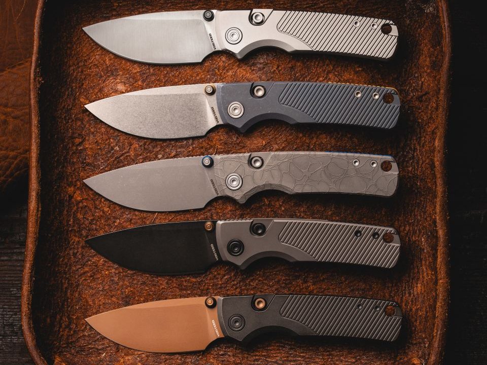 Several Ti-Slim Vosteed Porcupine top liner lock knives with buttons in a leather container