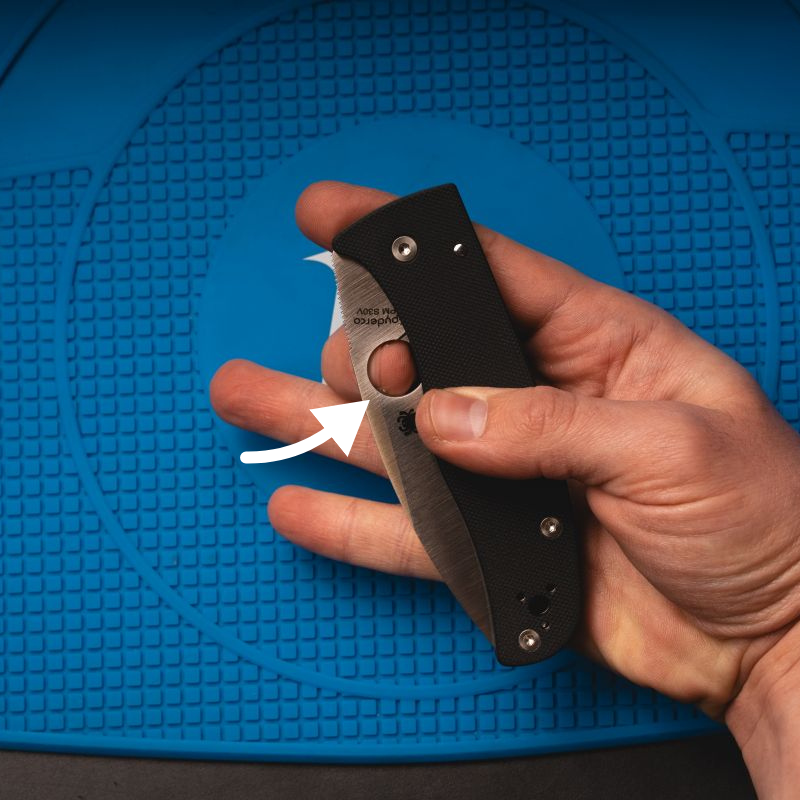 A man holding a Spyderco Bodacious, middle finger positioned to flick the knife open.