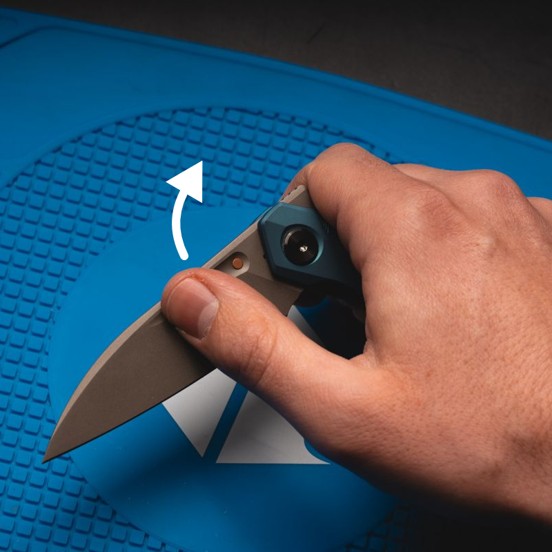 A man using the thumb groove opener on a blue Reate knife.