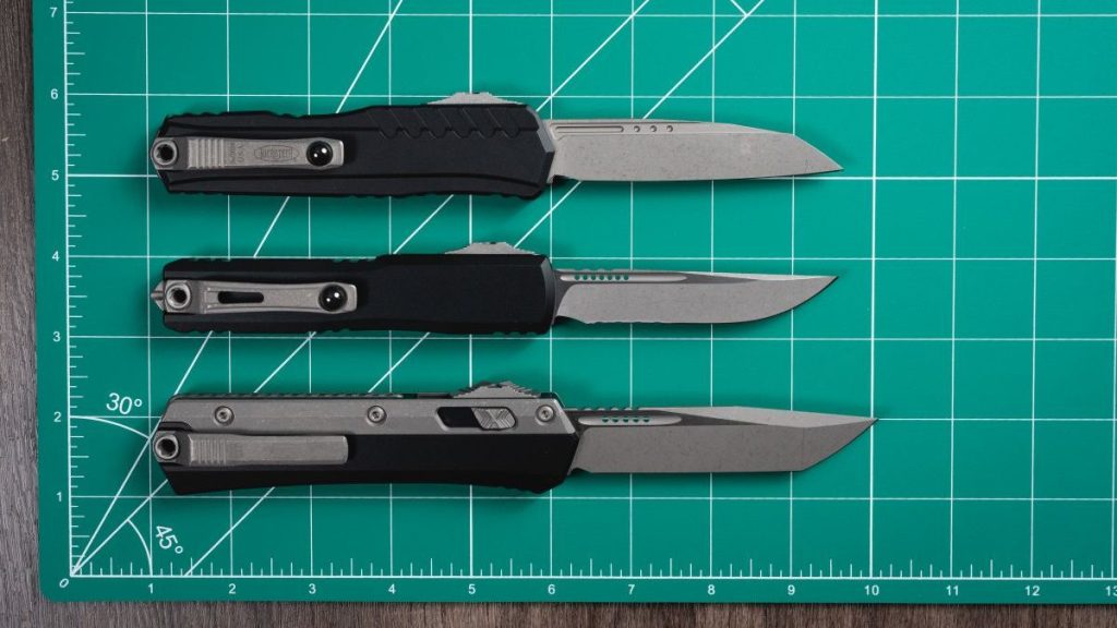 All medium Microtech OTF knives lined up on a green mat